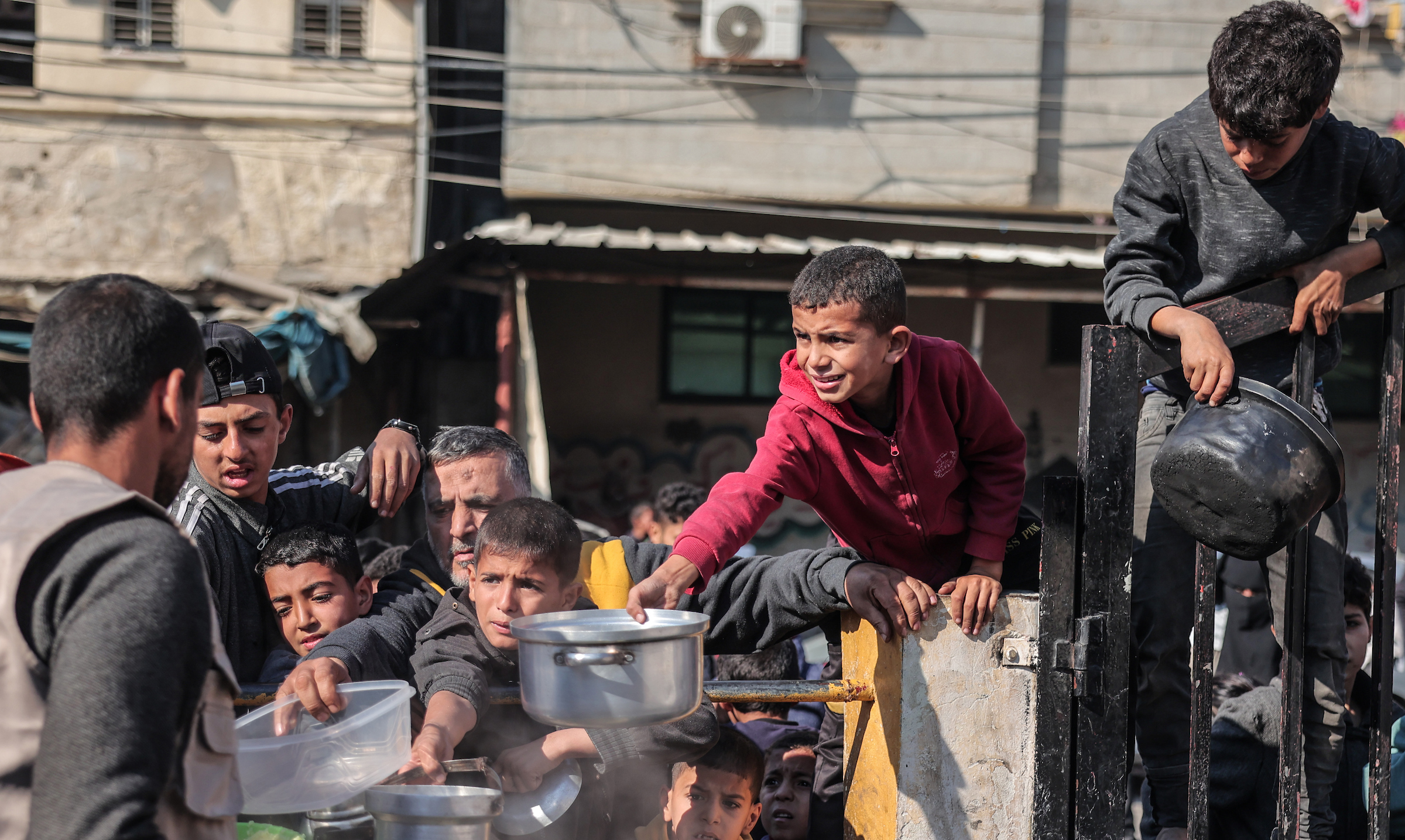 Palestinians gather with pots to receive food at a donation point provided by a charitable organization in Rafah in the southern Gaza Strip, on December 19, 2023. Photo by Bashar Taleb apaimages